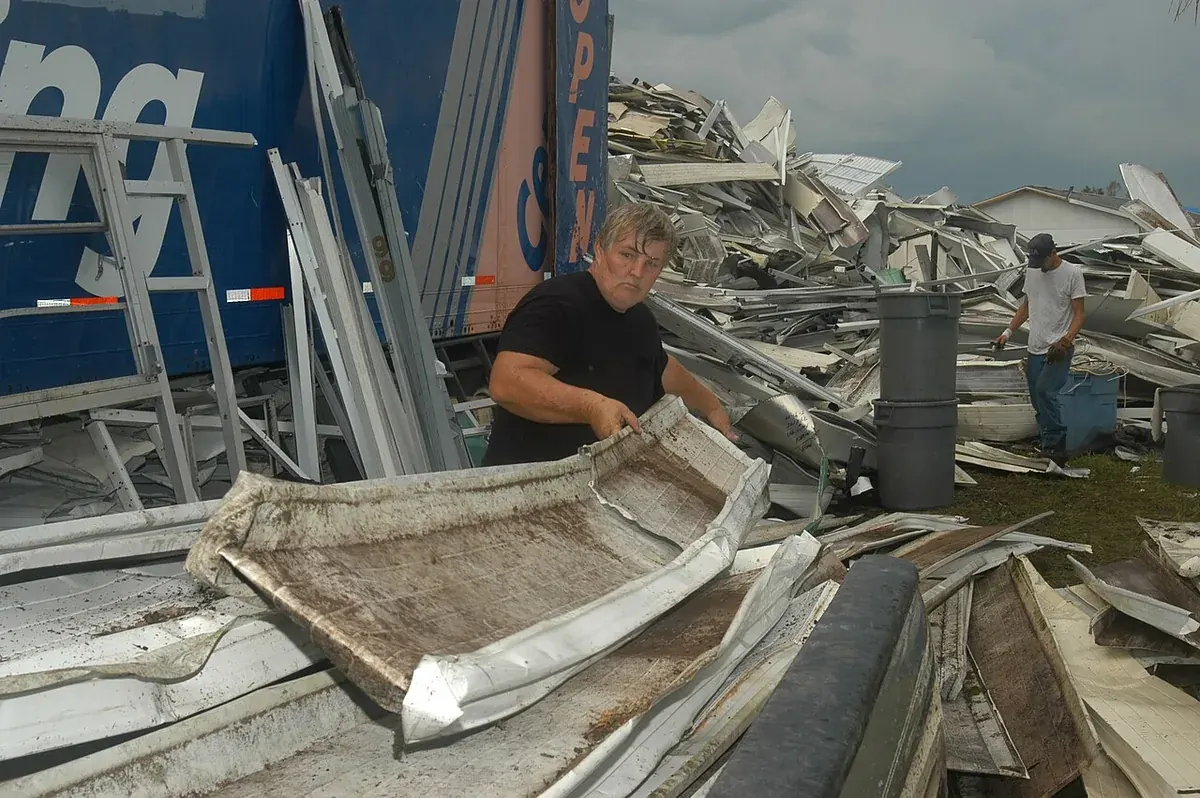 Workers sorting crumpled aluminum panels after Hurricane Charley in Hardee County, FL