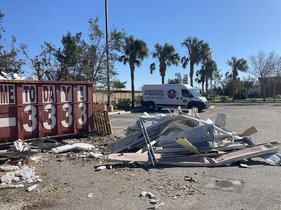 Pile of twisted white aluminum and building debris beside a dumpster after Hurricane Ian in Englewood, FL