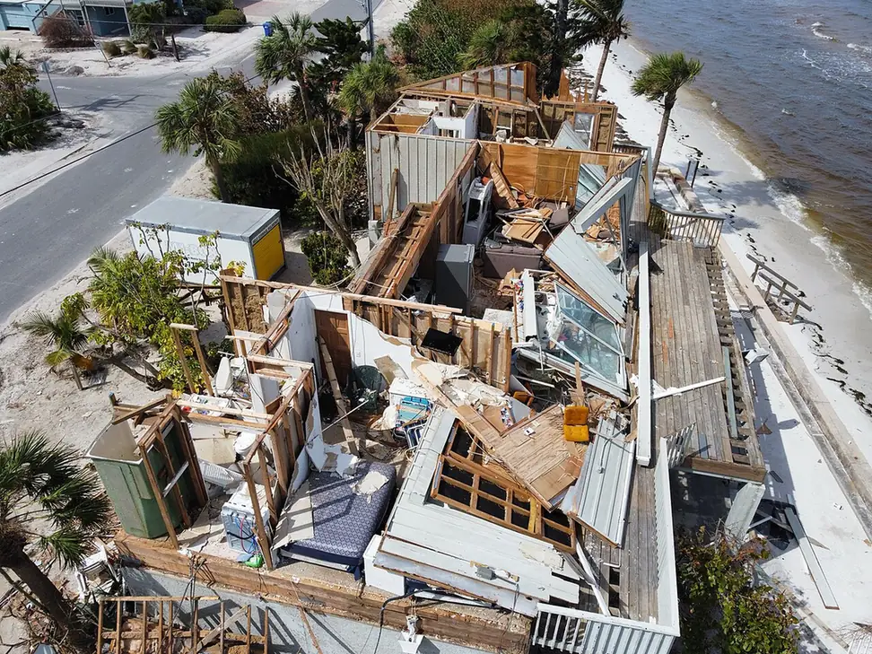 Aerial view of a beachfront house on Anna Maria Island in Manatee County, FL with its roof and walls torn open after Hurricane Milton