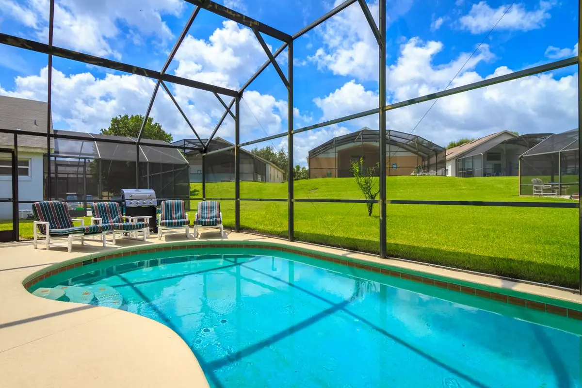 A screened pool enclosure over a backyard pool
