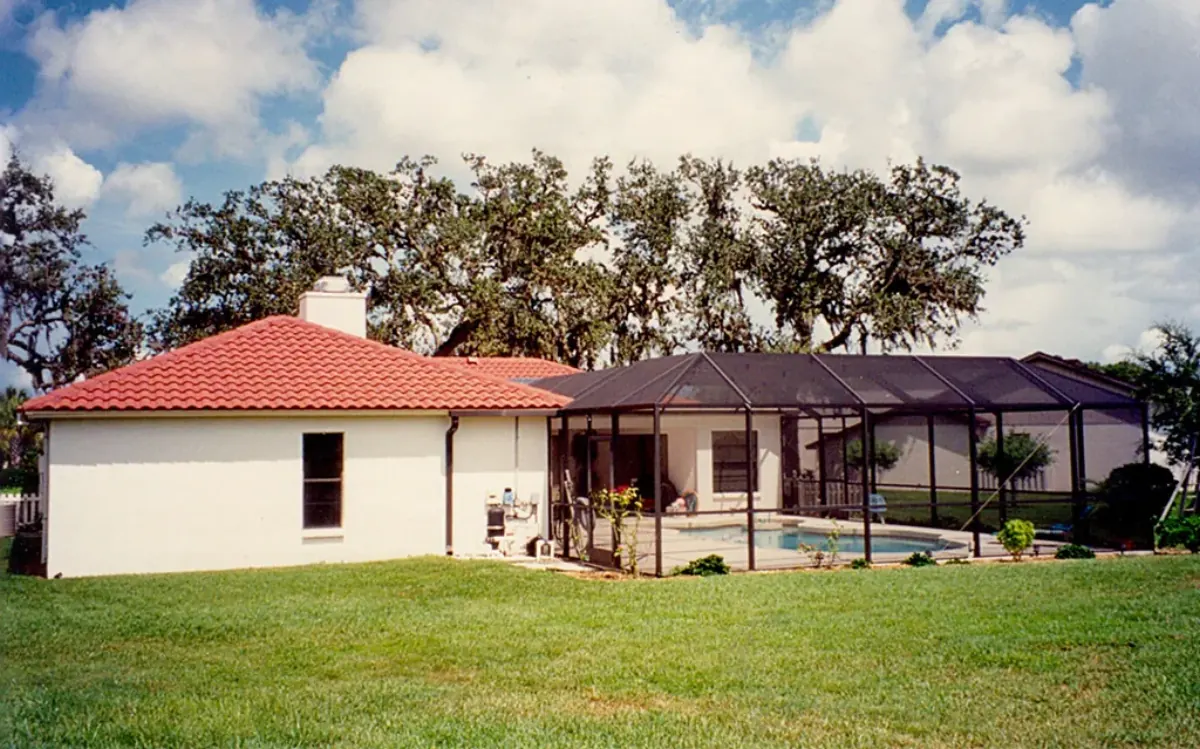 White stucco ranch house with a red barrel-tile roof and a long dark-framed pool cage, Sarasota County, FL