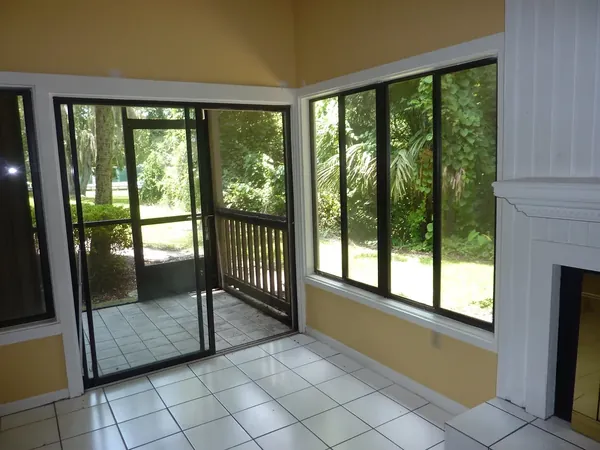 Tiled screen room with a black-framed screen door looking out to greenery