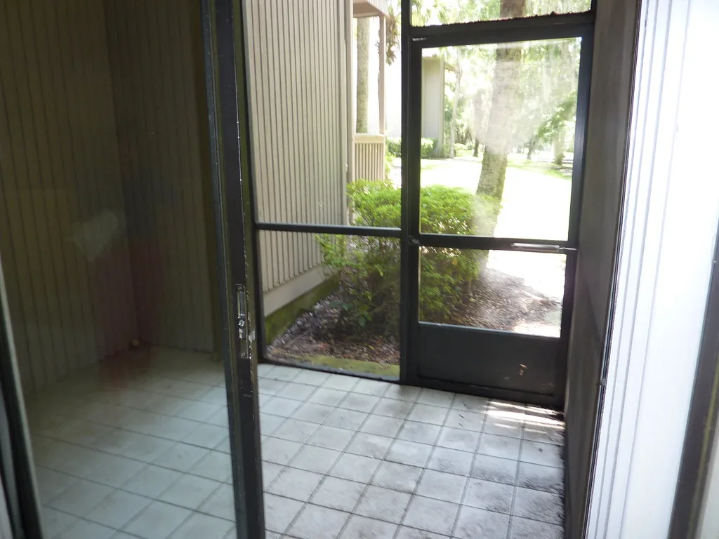 Aluminum screen door seen from inside a tiled screened patio