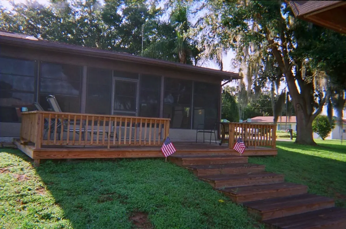 Screened porch above a wooden deck with oaks and Spanish moss