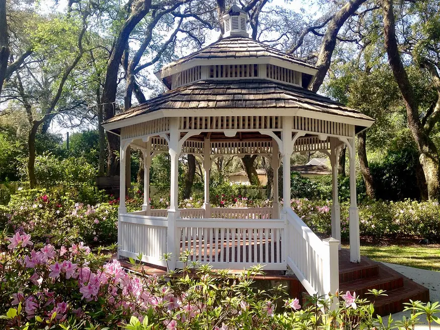 White gazebo surrounded by pink azaleas and oaks in Woodmont Park, Temple Terrace, FL