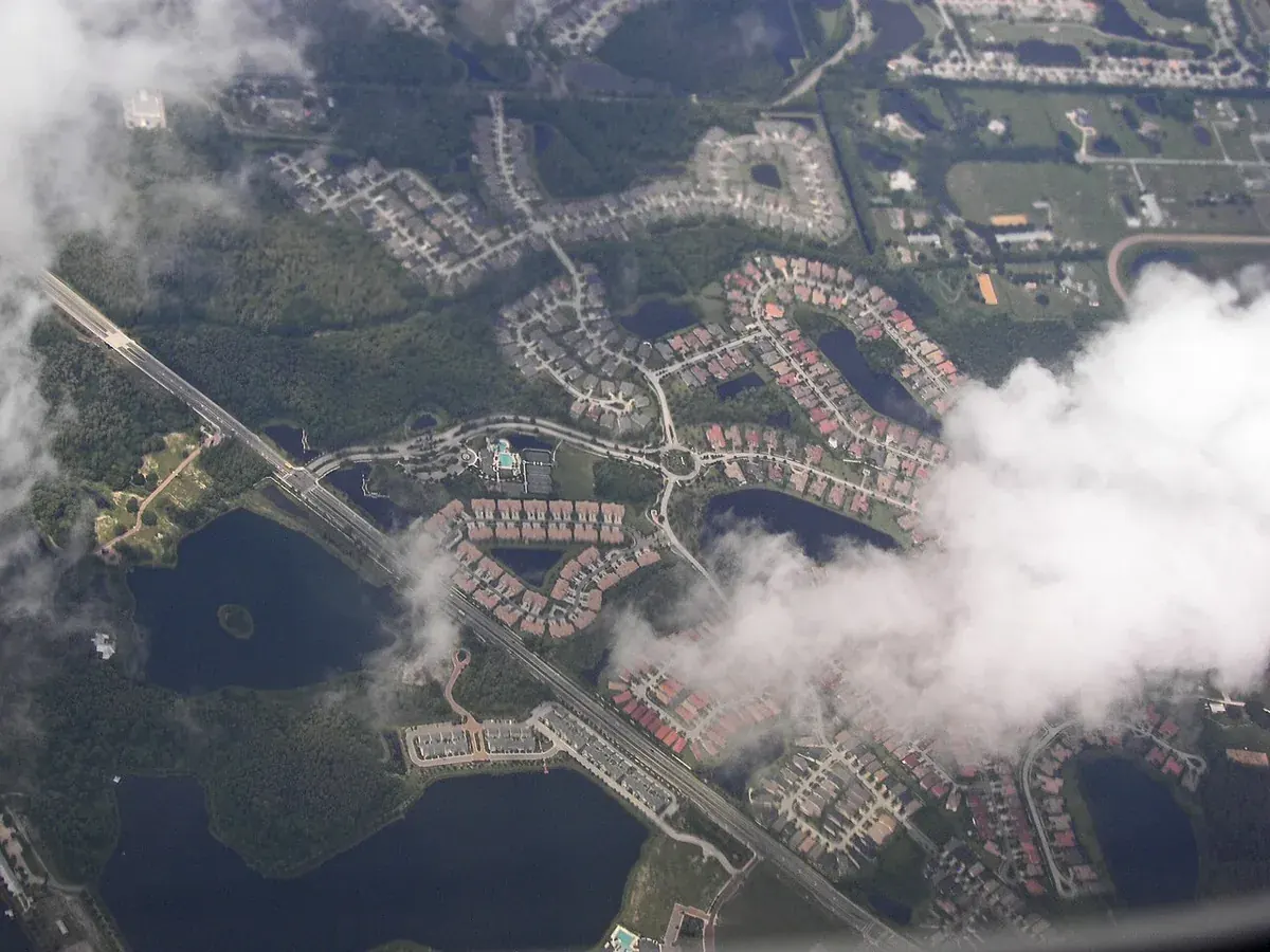 Aerial view of Westchase, FL neighborhoods, lakes and a highway partly under clouds